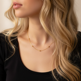 Close-up of a woman wearing a gold necklace with a plain background