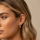 Close-up of a woman wearing gold hoop earrings with a neutral background