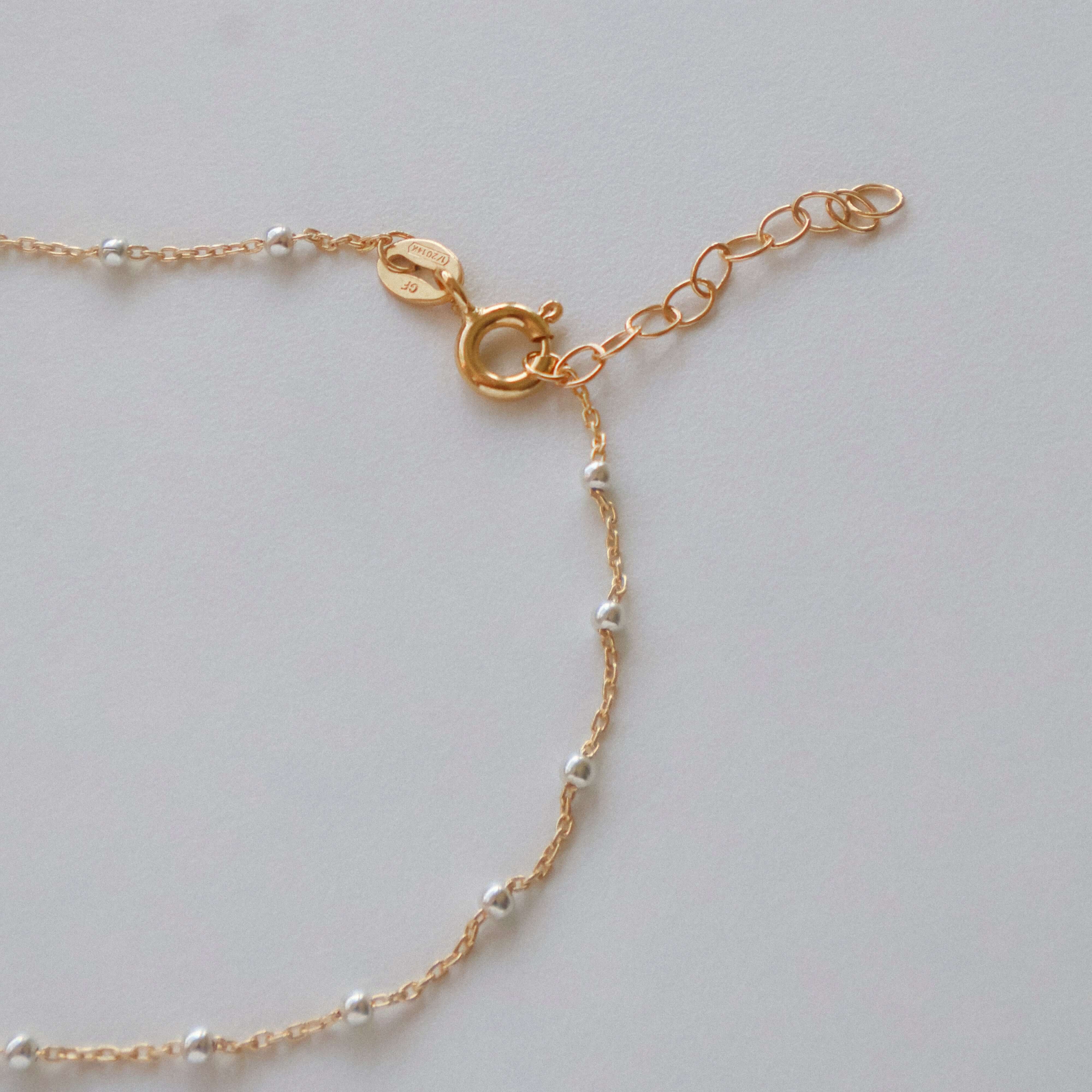 Close-up of the clasp and chain detail on a 14k Gold Satellite Bracelet with Sterling Silver beads.
