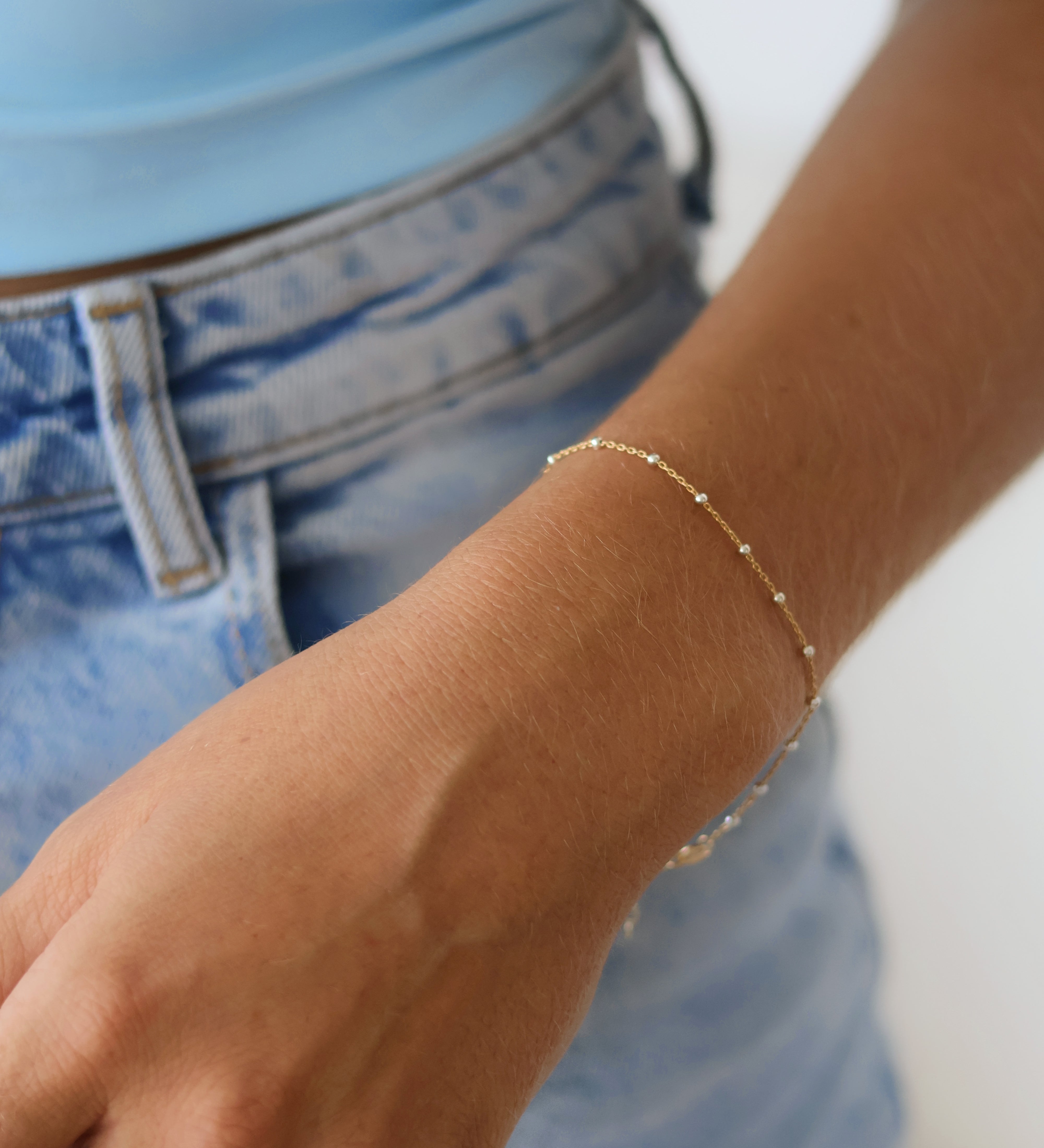 Stylish hand wearing a 14k Gold Satellite Bracelet with Sterling Silver Beads, showcasing mixed metal jewelry trend.